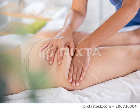 Hands of masseuse giving glutes and hamstring massage to woman 106736304