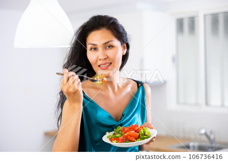 Portrait of positive woman in nightdress eating salad at home Portrait of positive woman in nightdress eating salad at home 106736416
