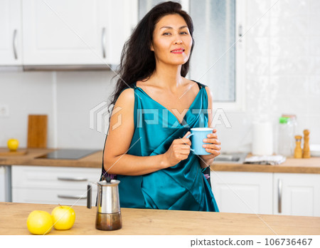 Portrait of positive woman in nightdress with mug of coffee 106736467