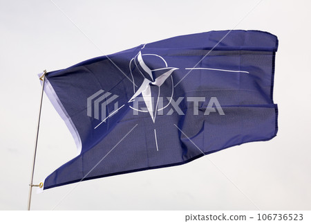 Flag of North Atlantic Treaty Organization against cloudy sky background 106736523