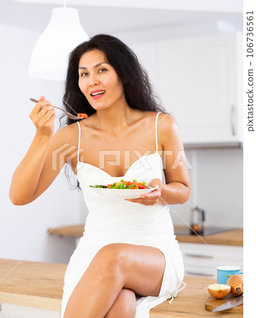 Portrait of positive woman in nightdress eating salad at home Portrait of positive woman in nightdress eating salad at home 106736561