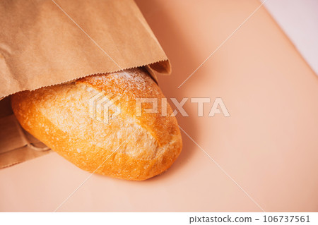 Freshly baked loaf of bread from a paper bag on the table Freshly baked loaf of bread from a paper bag on the table 106737561