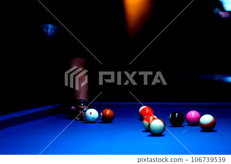 The hand holding the billiard cue, ready to make a precise strike on the billiard ball on the billiard table in a game of billiards. 106739539