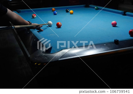 The hand holding the billiard cue, ready to make a precise strike on the billiard ball on the billiard table in a game of billiards. 106739541