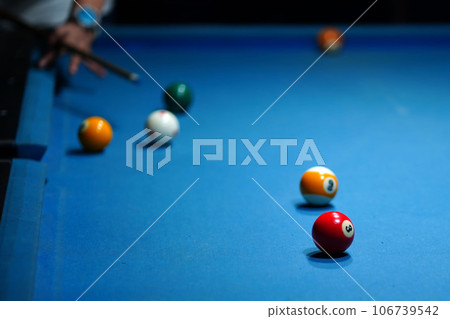 The hand holding the billiard cue, ready to make a precise strike on the billiard ball on the billiard table in a game of billiards. 106739542