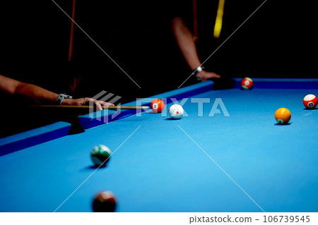 The hand holding the billiard cue, ready to make a precise strike on the billiard ball on the billiard table in a game of billiards. 106739545