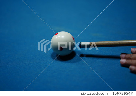 The hand holding the billiard cue, ready to make a precise strike on the billiard ball on the billiard table in a game of billiards. 106739547