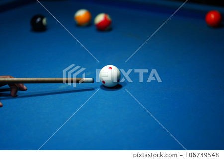 The hand holding the billiard cue, ready to make a precise strike on the billiard ball on the billiard table in a game of billiards. 106739548