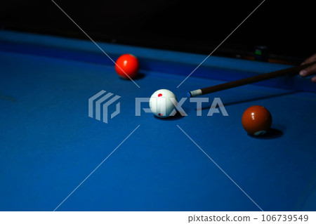 The hand holding the billiard cue, ready to make a precise strike on the billiard ball on the billiard table in a game of billiards. 106739549