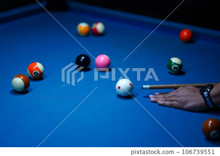 The hand holding the billiard cue, ready to make a precise strike on the billiard ball on the billiard table in a game of billiards. 106739551