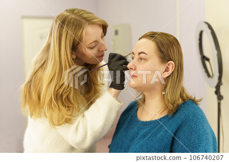 The master draws the shape of the eyebrows with white paint before eyebrow correction. Beauty industry. The master draws the shape of the eyebrows with white paint before eyebrow correction. Beauty industry. 106740207