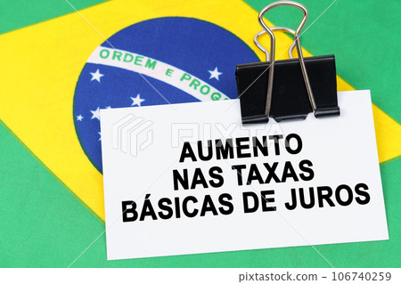 Economy and finance concept. On the flag of Brazil lies a business card with the inscription - increase in base interest rates. Text in Portuguese. 106740259