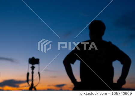 Blurred image of male photographer take a beautiful photograph of the sky when the sunrise or sunset. 106740969