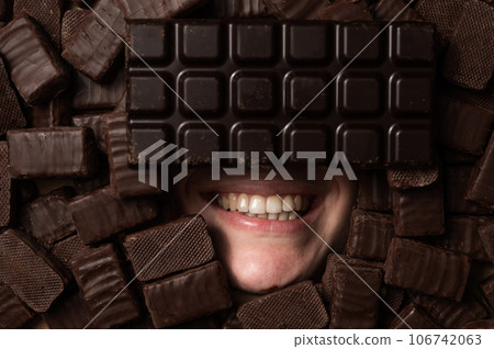 The face of a caucasian woman surrounded by sweets. Girl under a bunch of chocolates.  106742063