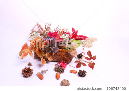 Colored leaves and nuts overflowing from a bamboo basket 1 Colored leaves and nuts overflowing from a bamboo basket 1 106742400