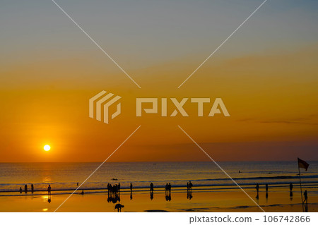The silhouette of people engaged in activities, enjoying the sunset on Kuta Beach in Bali. 106742866