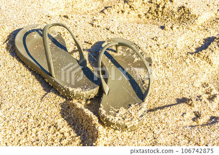 A pair of flip flops was left behind in the sandy shores of Melasti Beach, Bali, Indonesia. A pair of flip flops was left behind in the sandy shores of Melasti Beach, Bali, Indonesia. 106742875
