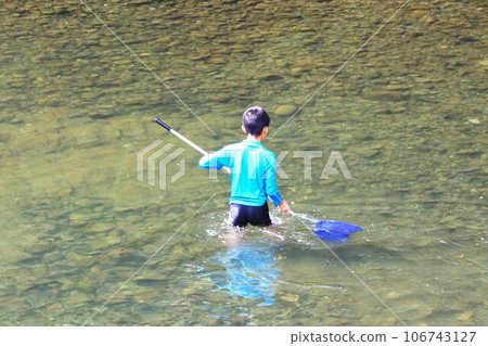 A scene of a boy catching fish with a net at the Miyako River in Tokigawa Town, a popular spot for river play. 106743127