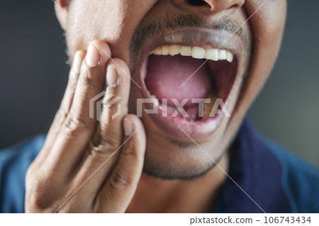 young man with sensitive teeth and glass of cold water . 106743434