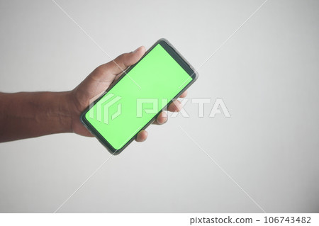 Close up of young man hand using smart phone with green screen  106743482