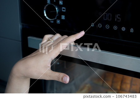 woman hand setting temperature control on oven. woman hand setting temperature control on oven. 106743483