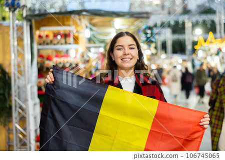 Cheerful girl with flag of Belgium at Christmas city market Cheerful girl with flag of Belgium at Christmas city market 106745065