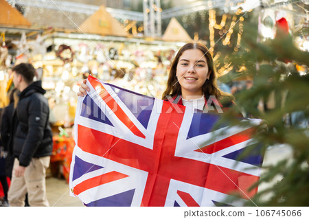 Young woman waving the United Kingdom flag at New Year street fair Young woman waving the United Kingdom flag at New Year street fair 106745066