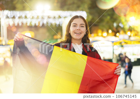 Smiling girl with flag of Belgium walking on street Christmas fair 106745145