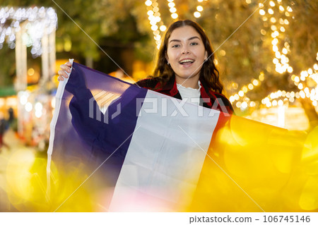 Smiling girl with flag of France walking on street Christmas fair 106745146