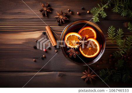 Autumn or winter coffee composition. Top view from above on glass cup of tea. Brown wooden table top with copy space, orange slices, anise stars, almond nuts, cinnamon sticks and pine branches Autumn or winter coffee composition. Top view from above on glass cup of tea. Brown wooden table top with copy space, orange slices, anise stars, almond nuts, cinnamon sticks and pine branches 106746533