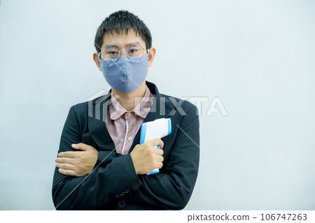 Man in black suit holding thermometer, standing in front of white background Man in black suit holding thermometer, standing in front of white background 106747263