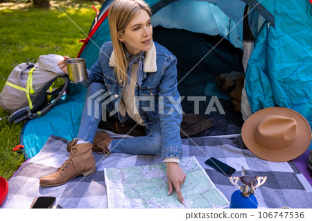 Blonde cute female traveler sitting near the tent in the forest 106747536