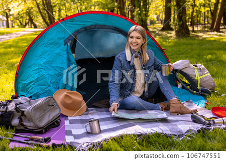 Blonde cute female traveler sitting near the tent in the forest 106747551