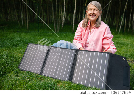 Woman holding solar panel in garden. 106747699