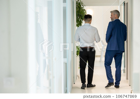 Men walking along corridor in office and talking about their work. Men walking along corridor in office and talking about their work. 106747869
