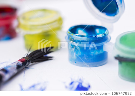 Jars with gouache paint and brush on white background.  106747952