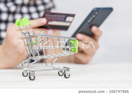 Shopping Cart and woman holding credit card and smartphone shopping online Shopping Cart and woman holding credit card and smartphone shopping online 106747966