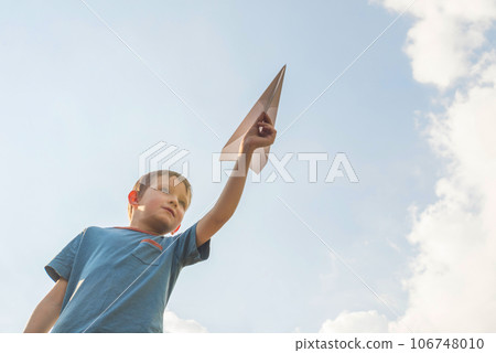 Little boy launches a paper plane into the air. Child launches a paper plane 106748010