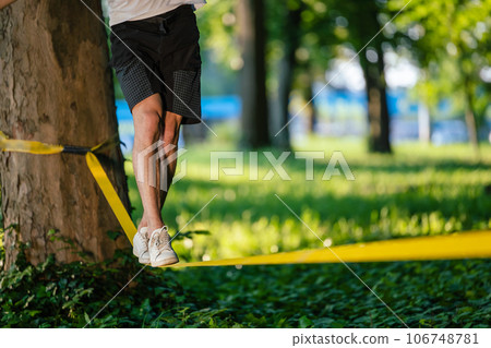 Man experiencing slacklining in the park 106748781