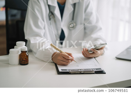 Male doctor working on desk with laptop computer and paperwork in the office. Medical and doctor concept. Male doctor working on desk with laptop computer and paperwork in the office. Medical and doctor concept. 106749581
