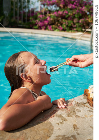 The girl is going to eat sushi by the swiming pool 106749619