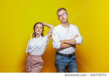Strong couple woman and man standing against bright orange studio wall background 106749733