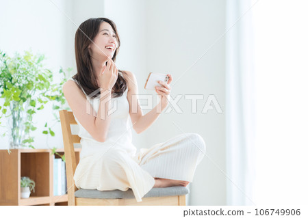 A young woman operating a smartphone in the living room A young woman operating a smartphone in the living room 106749906