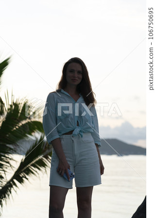 portrait of brunette girl standing at dawn against a palm tree portrait of brunette girl standing at dawn against a palm tree 106750695