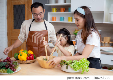 Happiness asian family with father, mother and daughter preparing cooking salad vegetable food. 106751220