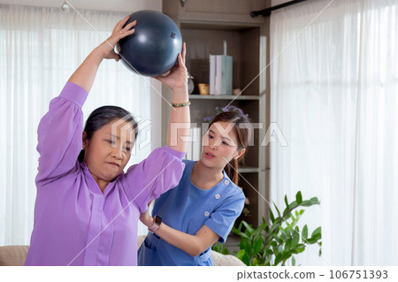 Asian caregiver woman or nurse training senior woman lifting sport ball with hands for exercise. Asian caregiver woman or nurse training senior woman lifting sport ball with hands for exercise. 106751393