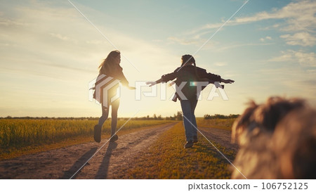 group children and dog running in the park at sunset. happy family freedom a kid dream concept. children kids running along the road in the park in nature sunset view lifestyle from the back 106752125