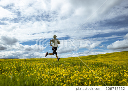 Woman trail runner cross country running at high altitude flowering mountain 106752332