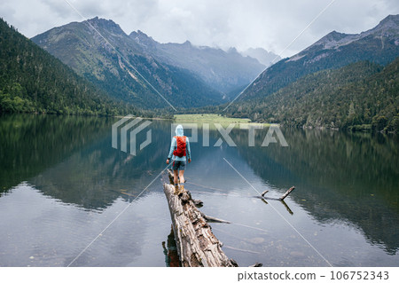Hiking woman walking on a one plank bridge in high altitude mountains 106752343