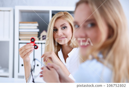 Business woman relaxes in the office turns antistress toy spinner 106752802